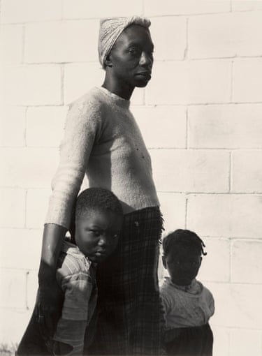 a black and white photo of a mother with her two young children