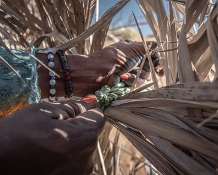 Closeup of a woman’s hands as she helps to make a barrier out of palm fronds.