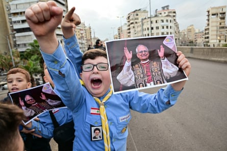 A boy in a scout uniform waves a picture of Pope Leo