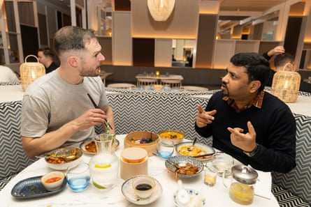 Peter and Akshat chatting and eating at a restaurant table