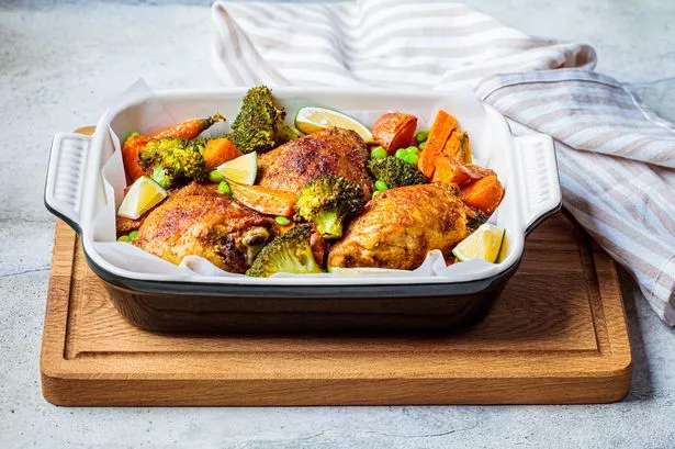 Baked chicken with vegetables, gray background.