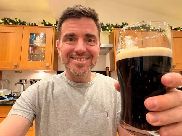 Steffan Rhys takes a selfie while holding up a pint of Guinness in a pint glass to the camera
