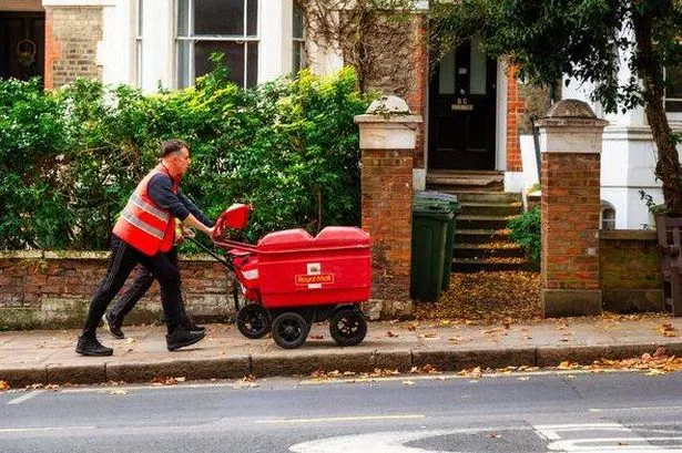 Royal Mail postman pushing mail trolley on London city street
