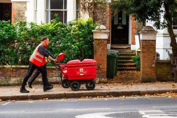 Royal Mail postman pushing mail trolley on London city street