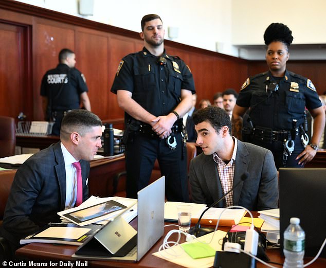 Mangione seen speaking with his attorney as two NYPD officers guard him inside Manhattan Supreme Court on Monday