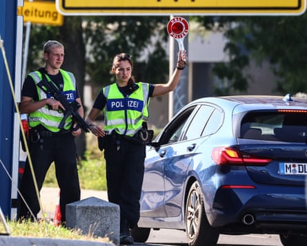Police officers stop a car at a checkpoint.