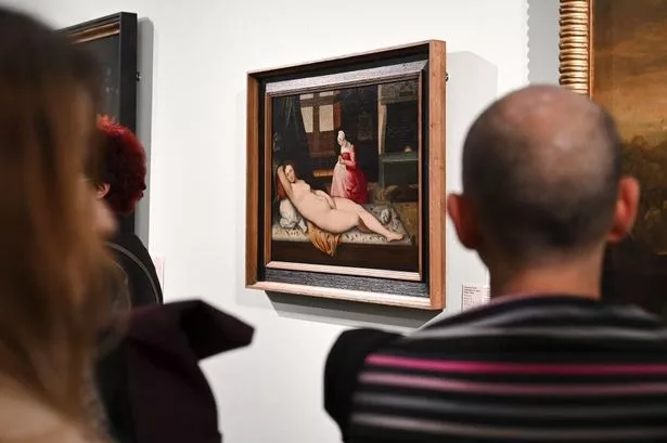 Visitors in a gallery looking at paintings during an exhibition of artworks that belonged to Jewish families and were looted by the Nazis during the World War II