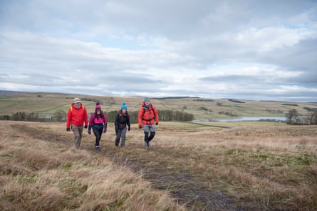 Four hikers dressed for tough conditions crossing moorland in northern England