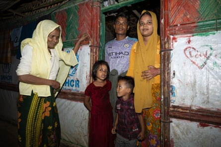 An older woman, two adults and two small children stand in a doorway